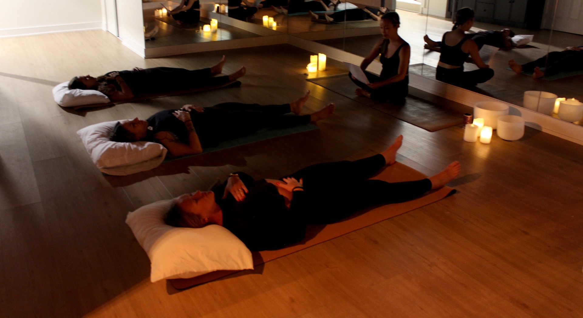 Participants resting on yoga mats during a candlelit Yoga Soma session